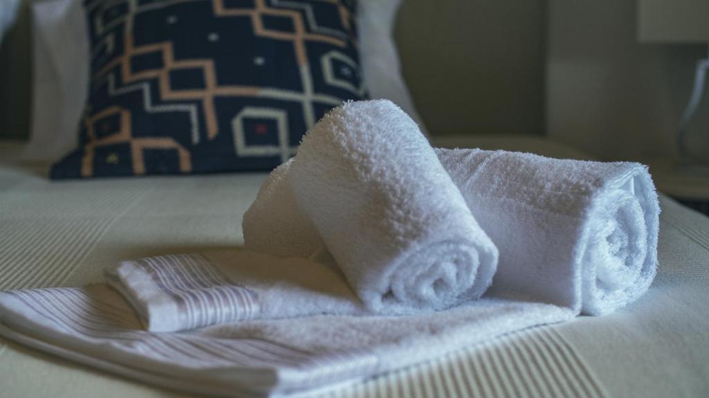 a pile of towels sitting on top of a bed at Pine House - Faro Airport, Beach and City Center in Faro