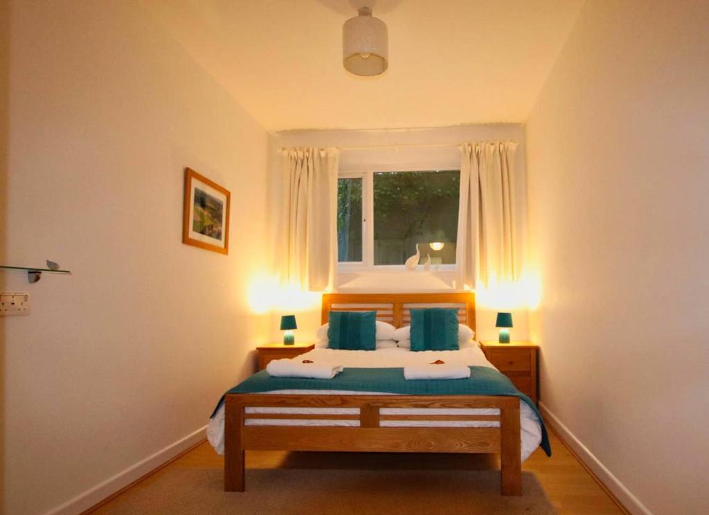 a bedroom with a bed with blue pillows and a window at Porthpean Apartment in Charlestown