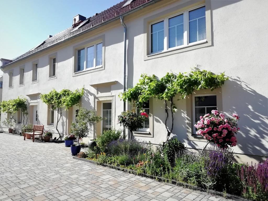 een wit huis met bloemen op de ramen bij Ferienhof Gräfe - 3-Seiten Hof mit großem Garten, Pool & Sauna in Meißen