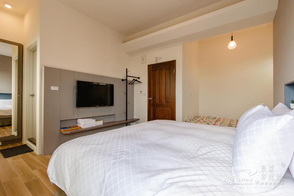 a bedroom with a large white bed and a flat screen tv at Xiao Tian Di Homestay in Taitung City