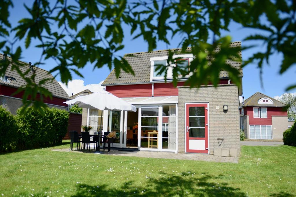 uma casa com uma porta vermelha e um pátio em Antibes 274 - Kustpark Village Scaldia em Hoofdplaat