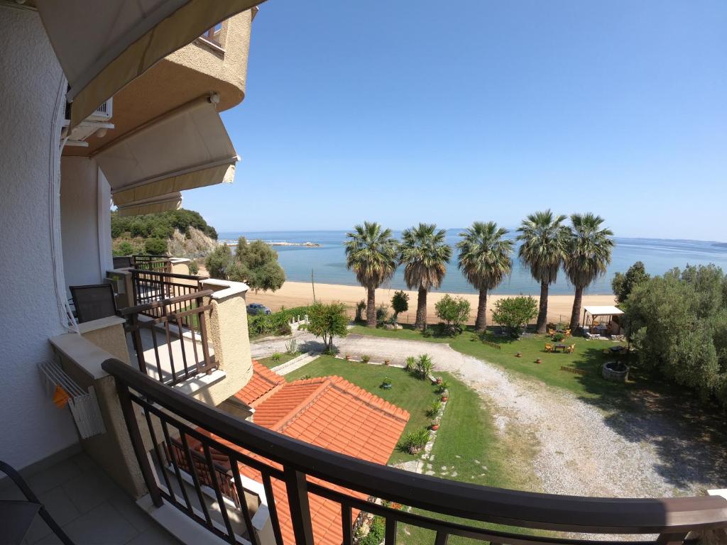 a balcony with a view of a beach and palm trees at Pension Karvounoskala in Stratoni