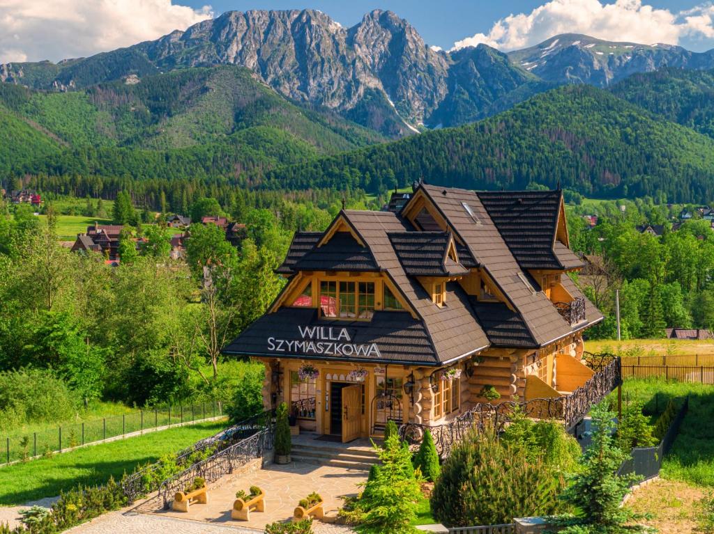 a log cabin with mountains in the background at Willa Szymaszkowa in Zakopane