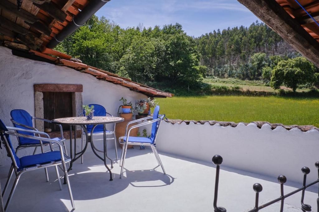 un patio con mesa, sillas y pared en A Charming , Traditional Cottage at Quinta da Ribeira en Vila Nova de Poiares