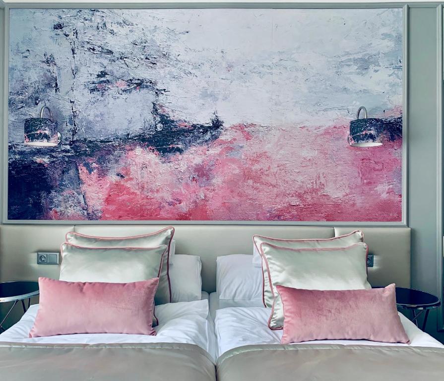 a painting above two beds with pink pillows at Boutique Hotel Center in Kecskemét