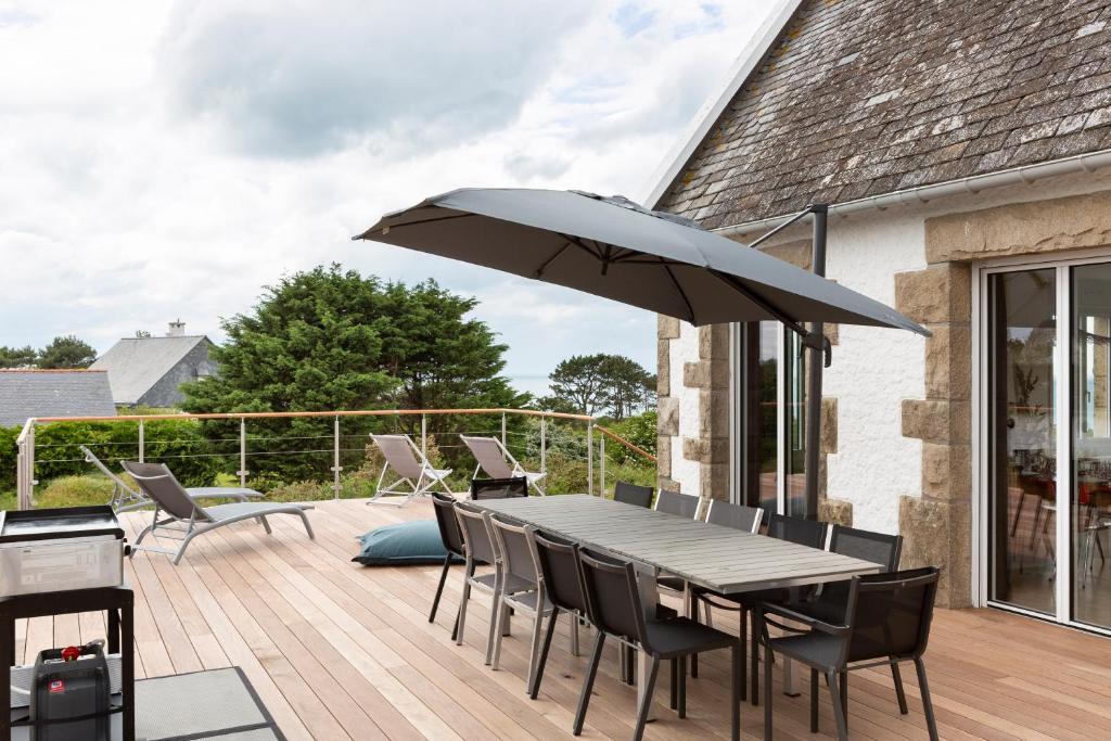 une terrasse avec une table, des chaises et un parasol dans l'établissement Le Sémaphore - Maison avec vue face à la mer, à Cancale