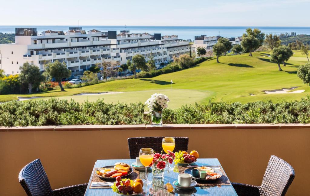 una mesa con comida y bebida en el balcón de un complejo en Ona Valle Romano Golf & Resort en Estepona