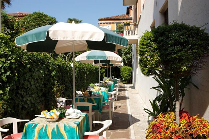 una fila de mesas con sillas y sombrilla en Hotel Santa Lucia, en Venecia