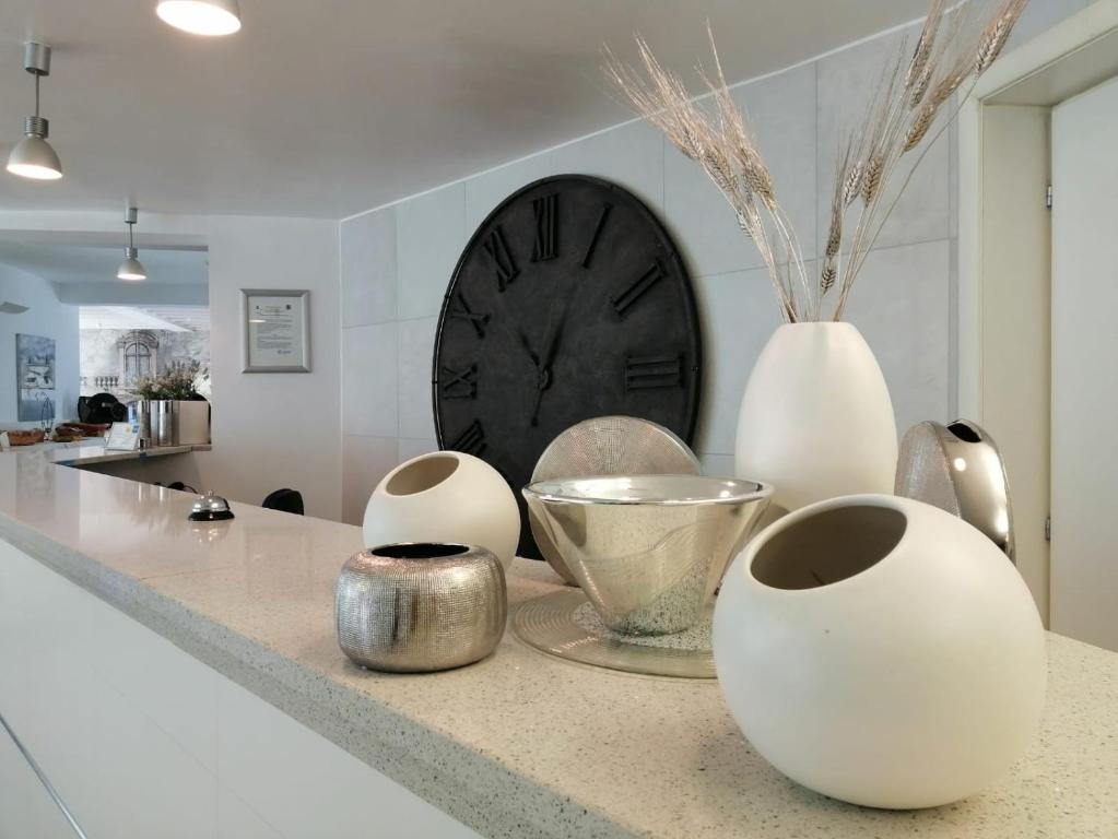 a counter with three white vases and a clock at Ahr Hotel Villa Alighieri in Stra