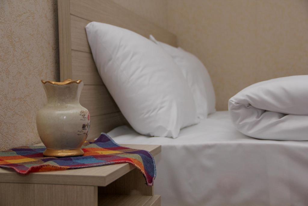 a bed with a white pillow and a vase on a table at Pearl apartment in Kutaisi in Kutaisi