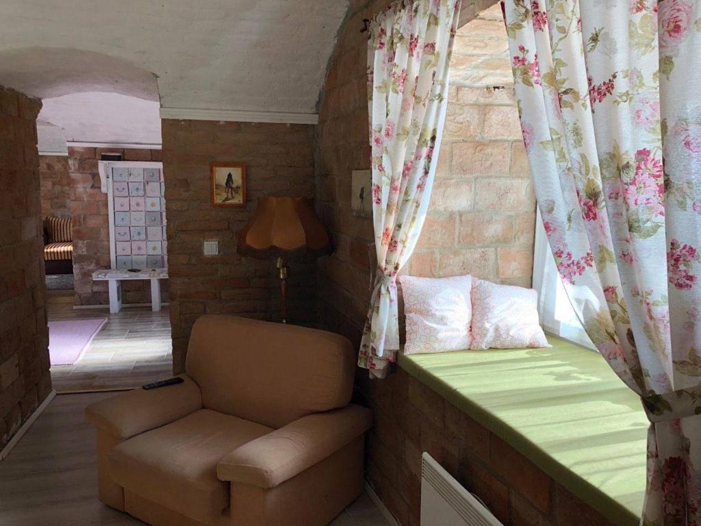 um quarto com uma cama, uma cadeira e uma janela em Kakukkfu Barlang-Vendeghaz em Noszvaj