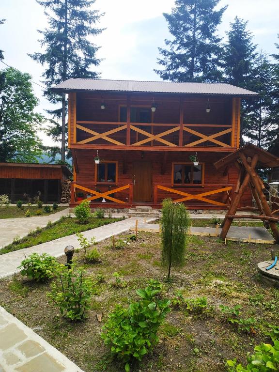 a large wooden building with trees in the background at House Beskyd in Skole