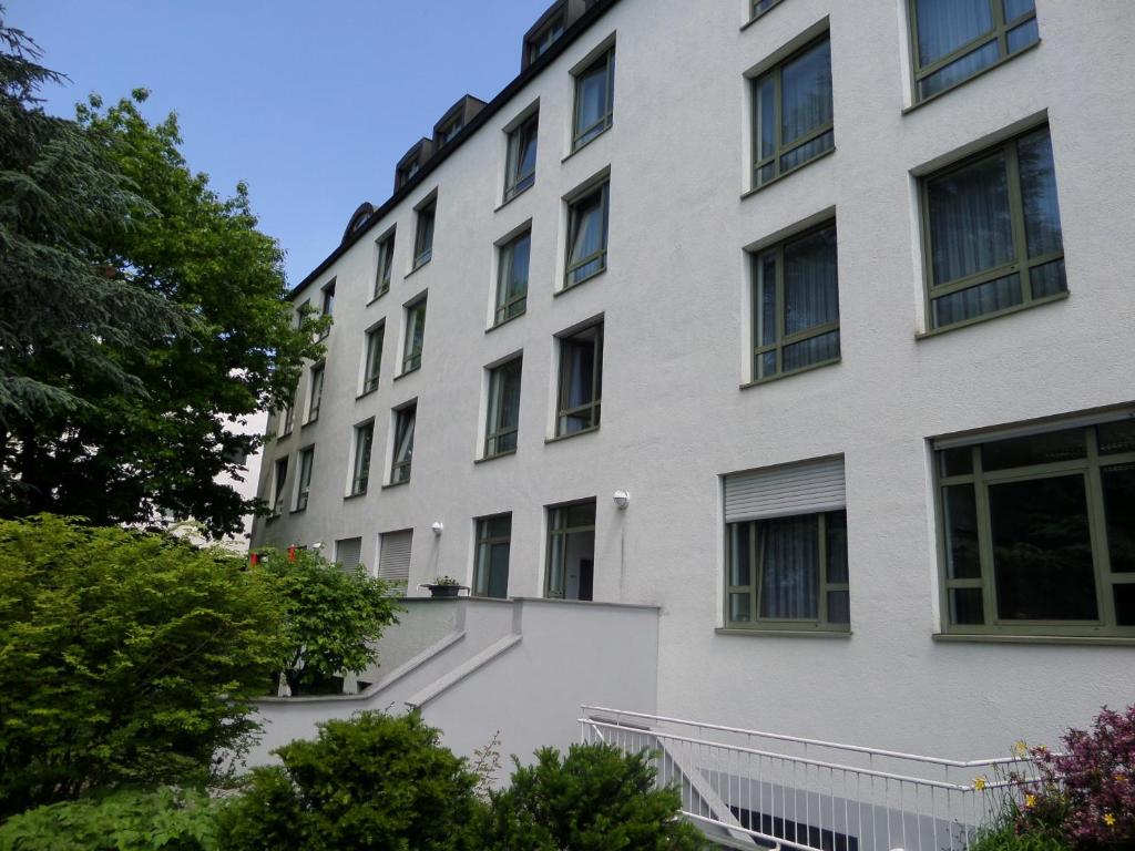 un gran edificio blanco con ventanas y árboles en Christkönigshaus en Stuttgart
