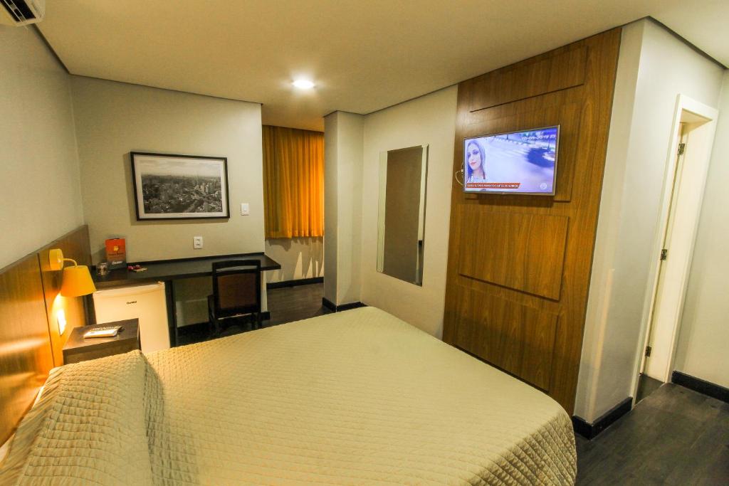 a bedroom with a bed and a desk and a television at Hotel Grand Barão in São Paulo