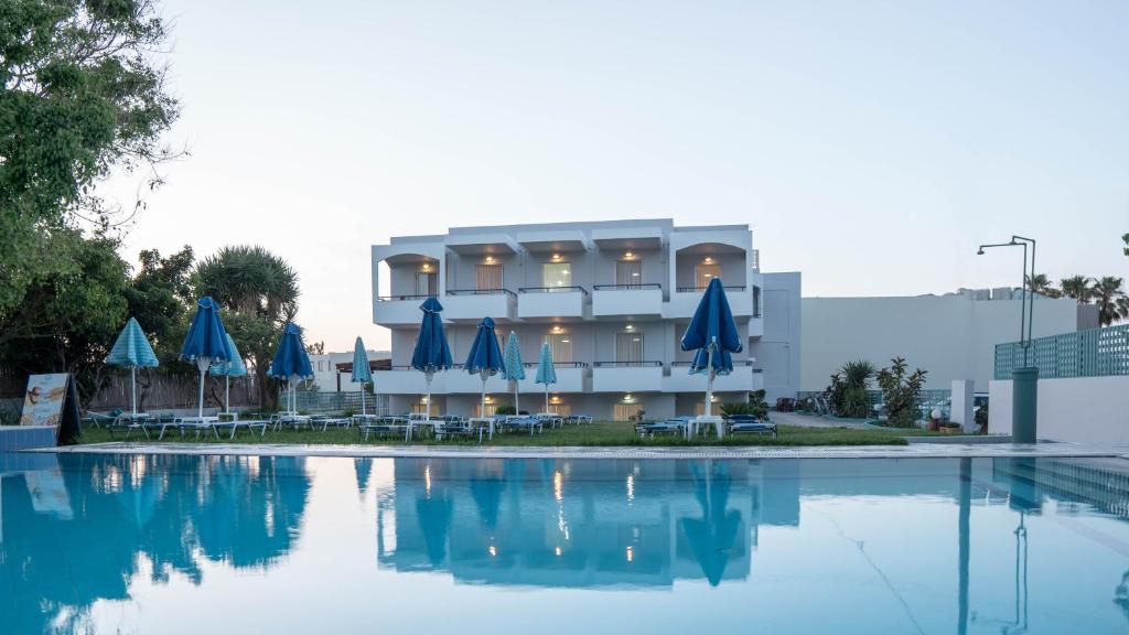 um edifício com guarda-sóis azuis e uma piscina em Pinelopi Hotel em Platanes