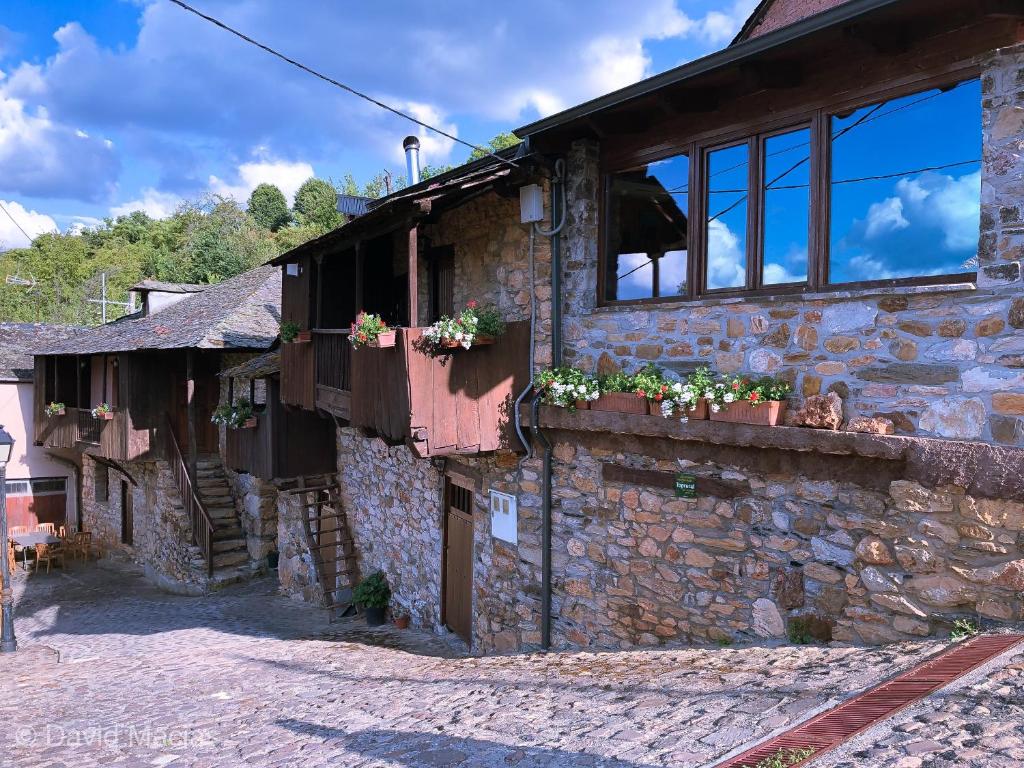 a stone building with windows and flowers on it at Hotel Rural El Lagar De Las Médulas in Orellán