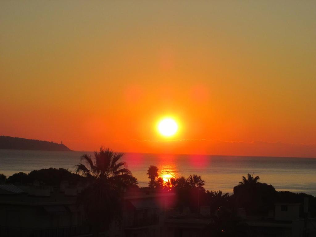 un coucher de soleil sur l'océan avec le soleil dans le ciel dans l'établissement Studio Californie, à Nice