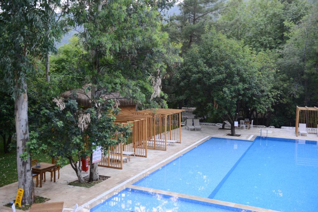 una piscina en un patio con mesa y árboles en Suna Village Hotel & Bungalow Fethiye, en Fethiye