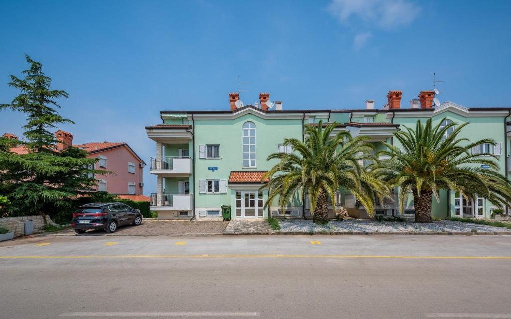 um grande edifício verde com palmeiras em frente em RIVA house with apartment em Crveni Vrh