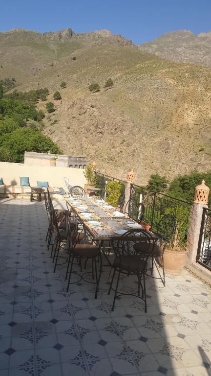 a dining table and chairs on a patio with a view at Toubkal Garden in Imlil