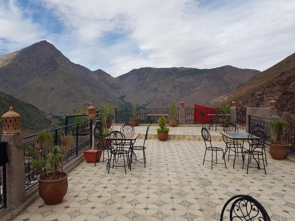 a patio with tables and chairs with mountains in the background at Toubkal Garden in Imlil