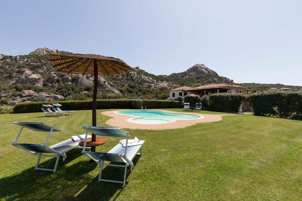 eine Gruppe Stühle und ein Regenschirm auf einem Hof in der Unterkunft Villa Iris with Pool in Baja Sardinia