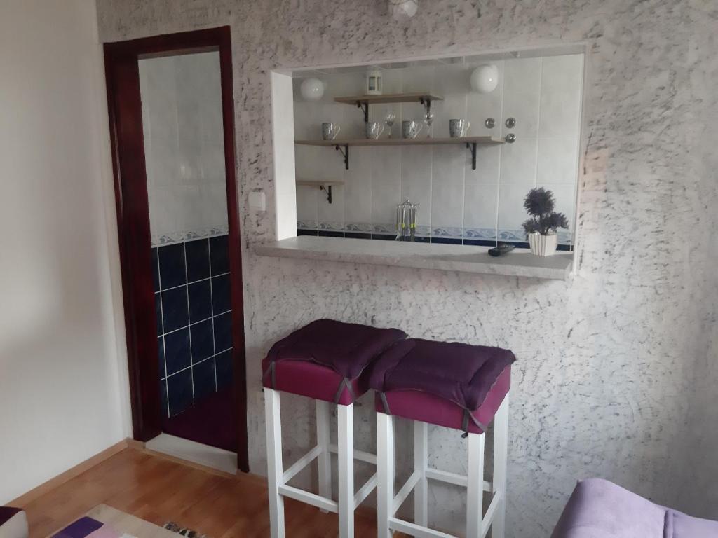 una cocina con 2 taburetes con cojines morados en Apartments Marina, en Petrovac na Moru