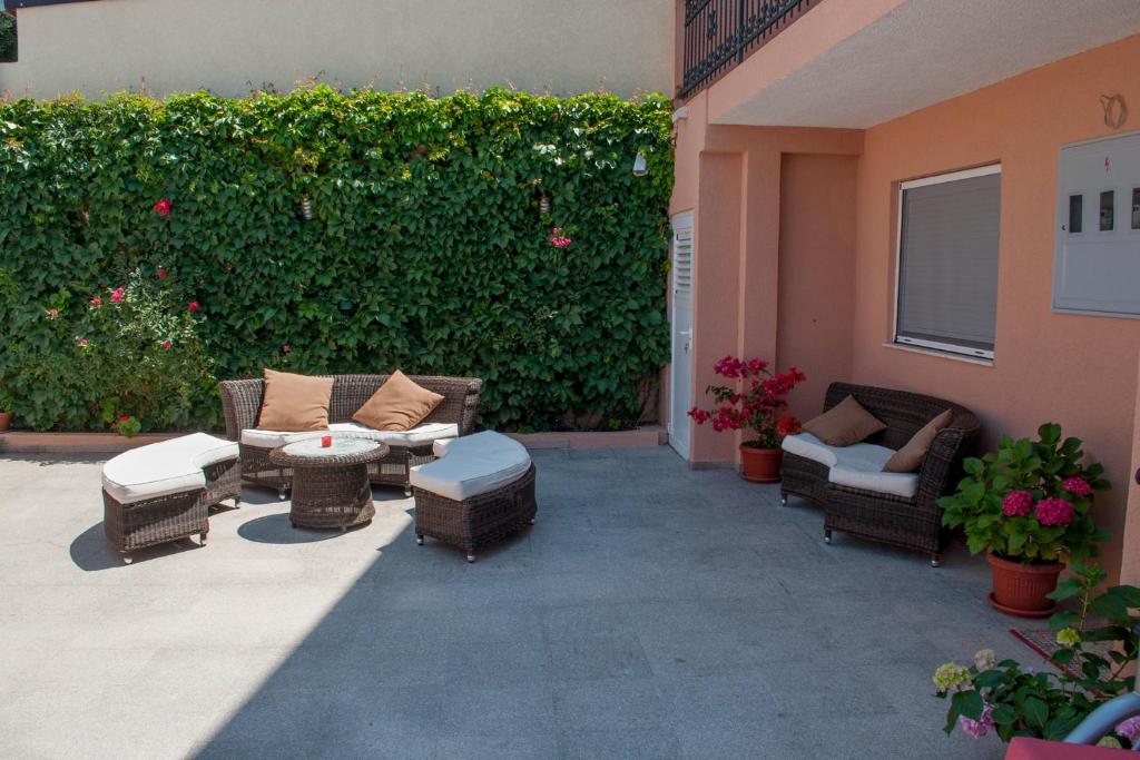 a patio with wicker chairs and tables and a green hedge at Apartments Villa Sveti Nikola in Budva