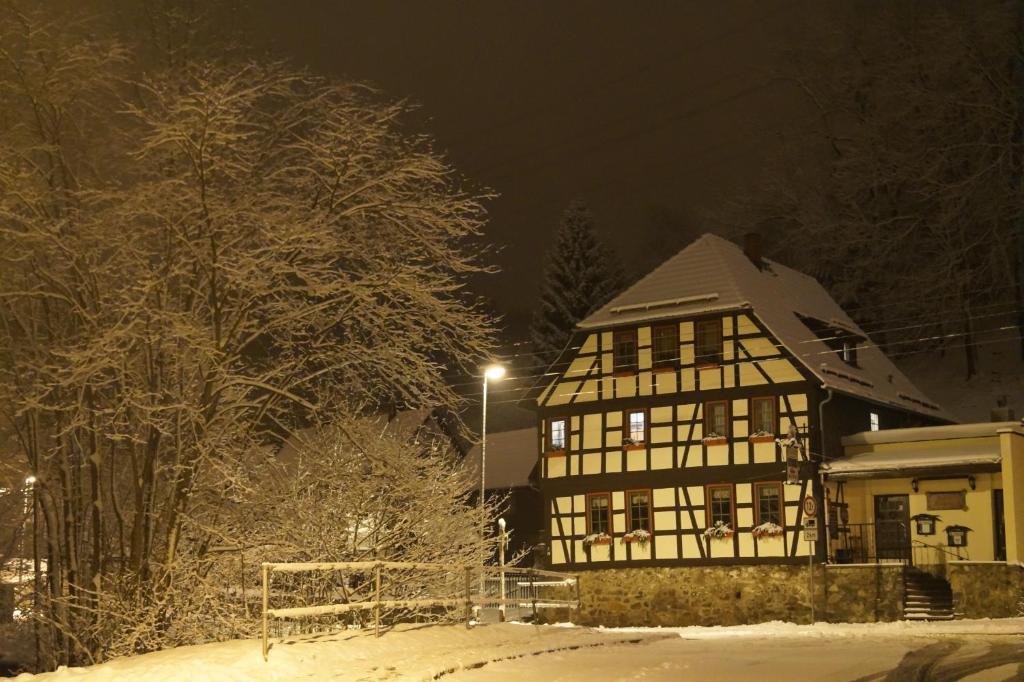 a house is covered in snow at night at Lauterer Wirtshaus in Suhl