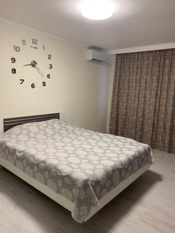 1 dormitorio con 1 cama y reloj en la pared en Apartments on Priportovaya,35, en Cherkasy