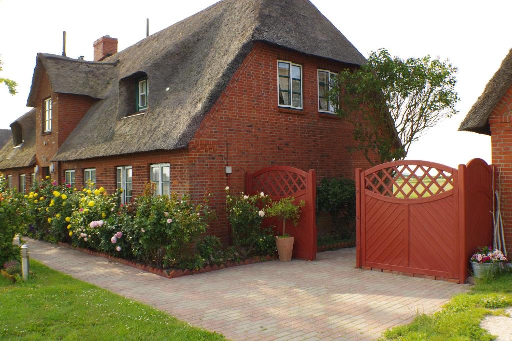 佩爾沃姆的住宿－Ferienwohnung I "Westermühle"，茅草屋顶和红色门的房子