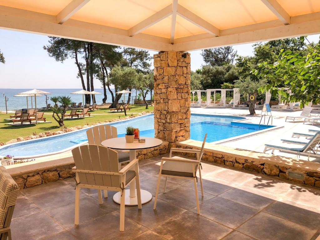 a patio with a table and chairs next to a swimming pool at Aroma Beach Hotel Bungalows in Limenas