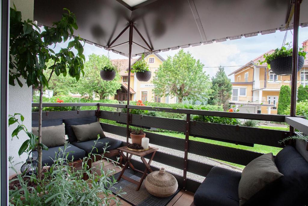 - un balcon avec des canapés bleus et un parasol dans l'établissement Apartment Galerija Bled, à Bled