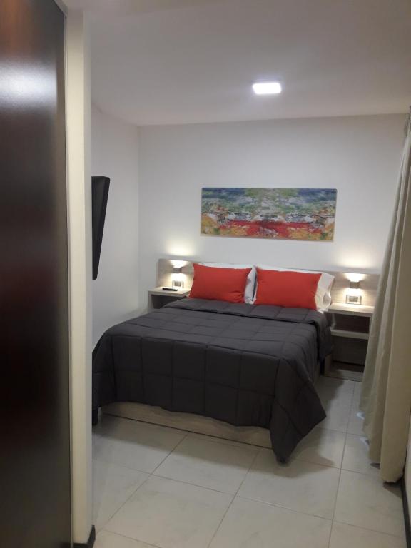 1 dormitorio con 1 cama con 2 almohadas rojas en Departamento Torre Sofitel en Río Cuarto