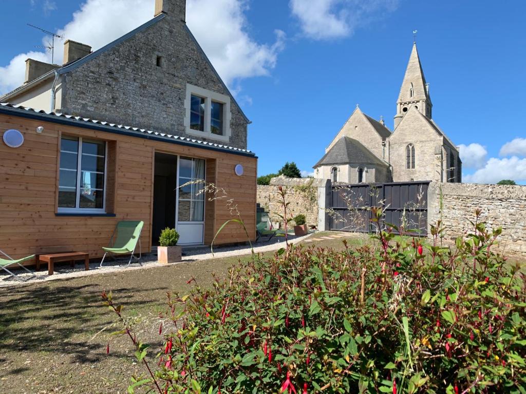 a house with a church in the background at Villa kahlo Omaha Beach in Colleville-sur-Mer