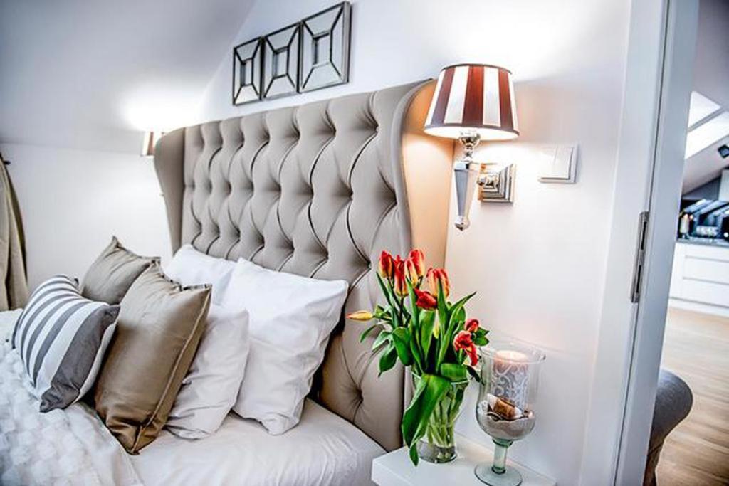 een slaapkamer met een wit bed en een vaas met bloemen bij Moon River Apartments Gdansk Old Town in Gdańsk