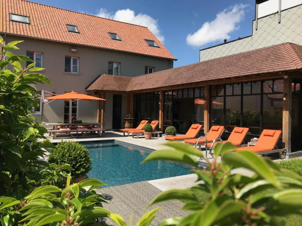 een huis met een zwembad en oranje stoelen bij B&B d'Oude Brouwerij in De Haan
