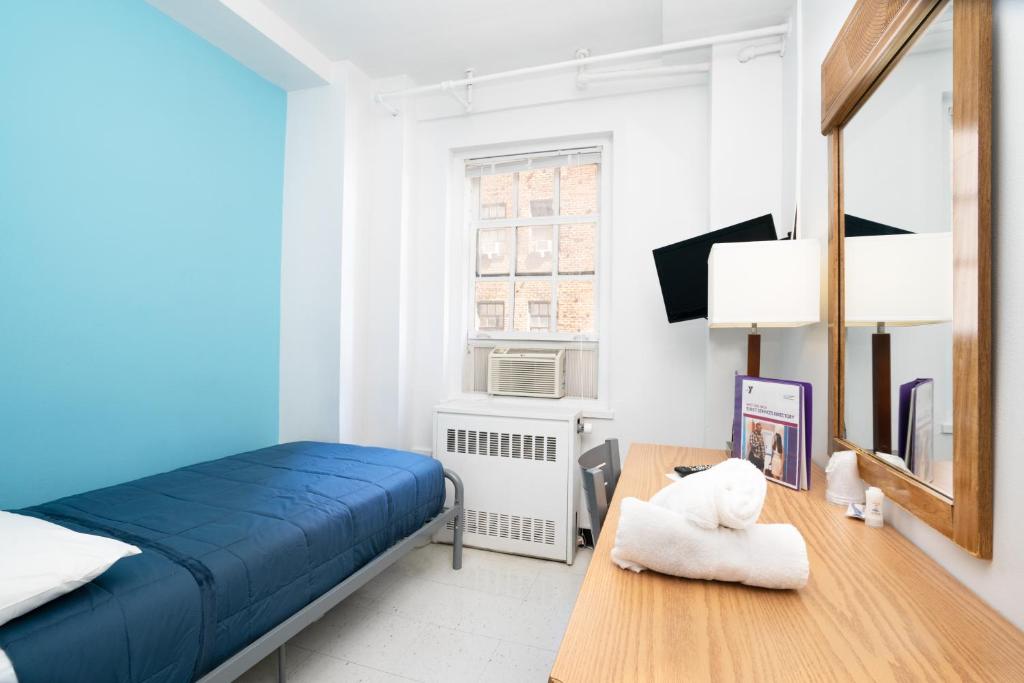 Schlafzimmer mit einem blauen Bett und einem Holztisch in der Unterkunft West Side YMCA in New York