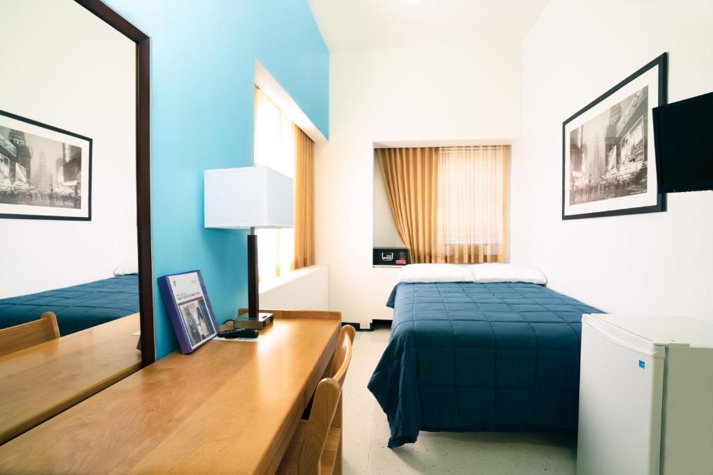 ein Schlafzimmer mit einem Bett und einem Schreibtisch mit einem Schreibtisch in der Unterkunft West Side YMCA in New York