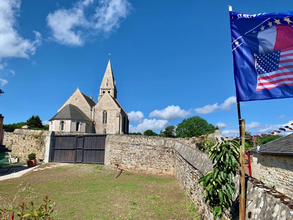 una bandera frente a un castillo con una iglesia en Villa kahlo Omaha Beach en Colleville-sur-Mer