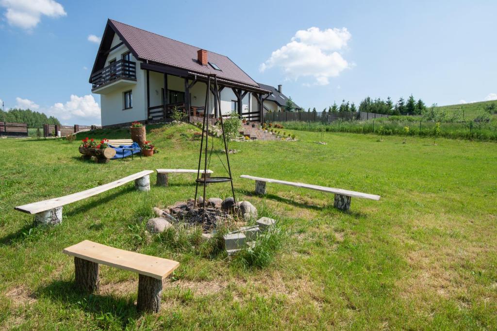 una casa con mesa de picnic y bancos en un campo en Willa Liski en Stare Juchy