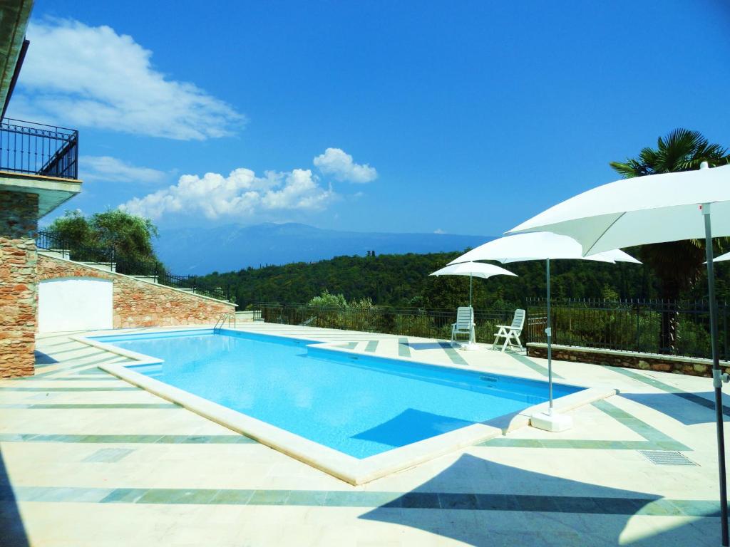 a swimming pool with an umbrella next to a house at Albatros in Toscolano Maderno