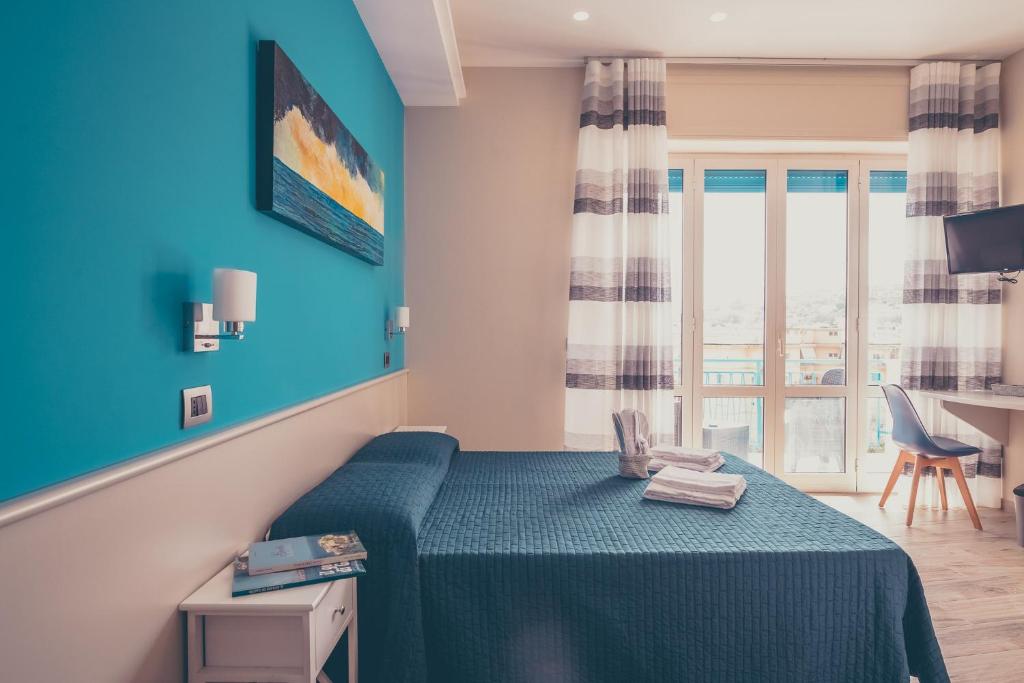 una camera da letto con un letto con pareti blu e una finestra di Oltre il Mare Guest House a Gaeta