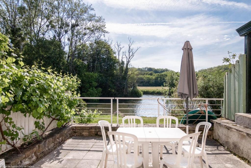 eine Terrasse mit einem Tisch, einem Sonnenschirm und einem Fluss in der Unterkunft Gîte La Saônoise in Conflandey