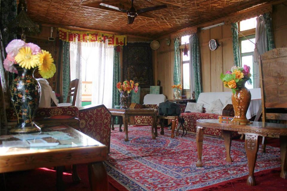 a living room with two vases of flowers on a rug at Houseboat Pride of India in Srinagar