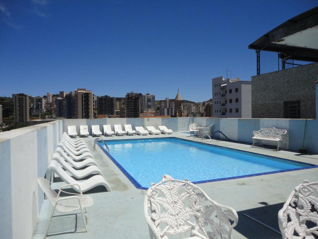a pool on the roof of a building with lounge chairs at Jóia Hotel in Poços de Caldas