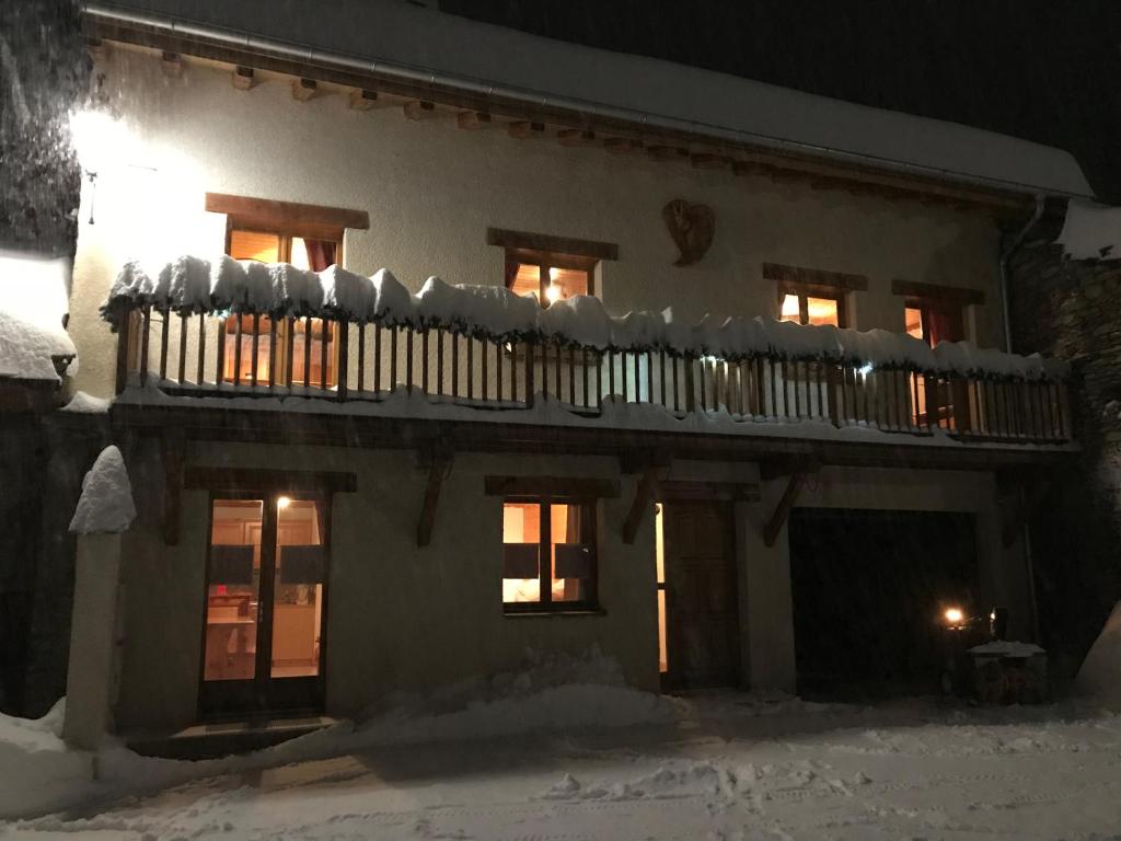 a house with a balcony in the snow at night at Chalet L’Etagne in Bessans