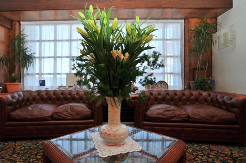 una sala de estar con sofá y un jarrón con flores sobre una mesa en Hotel Ristorante Al Sorriso en Soriso