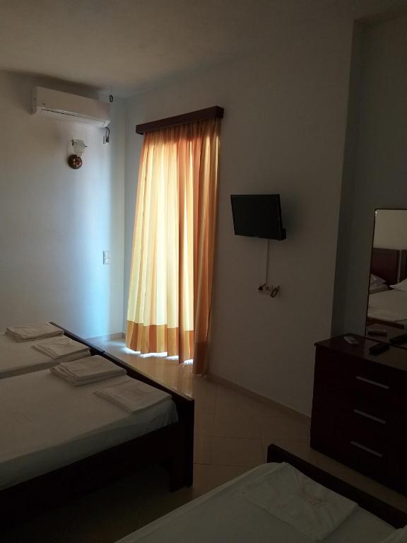 a hotel room with two beds and a window at Hotel Afrodite in Dhërmi