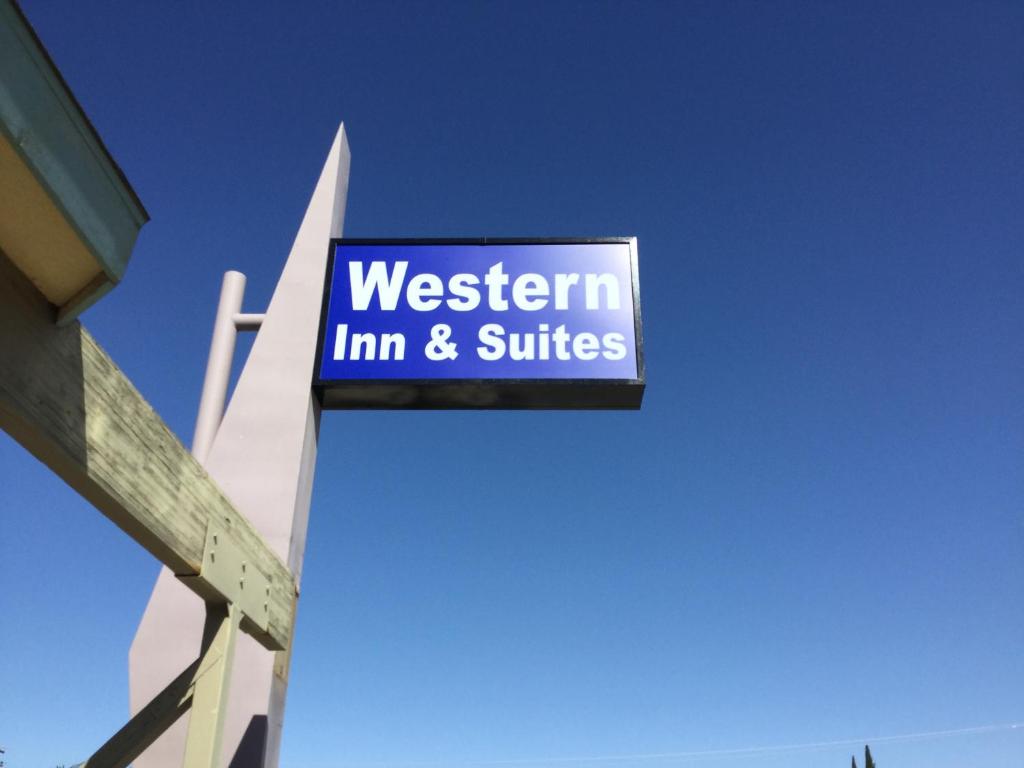 ein Schild für den westwegischen Gasthof und die Suiten auf der Seite eines Gebäudes in der Unterkunft Western Inn & Suites in Taft